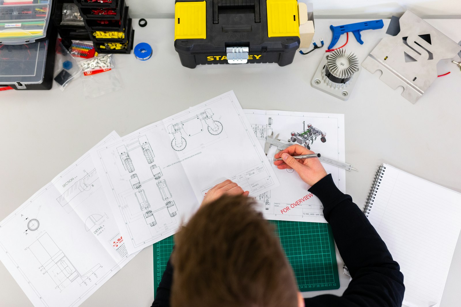 Engineering drawings and a prototype on a desk